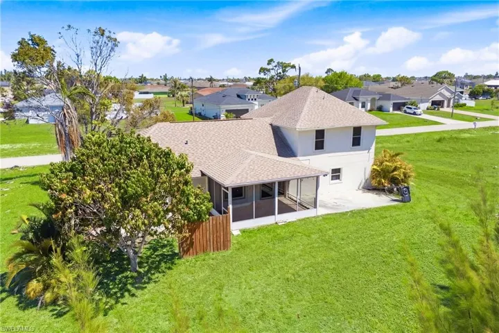 Elevated view highlights the backyard paradise with tropical trees, open outdoor living space, and shimmering canal waters—the ultimate retreat for relaxation and entertaining.