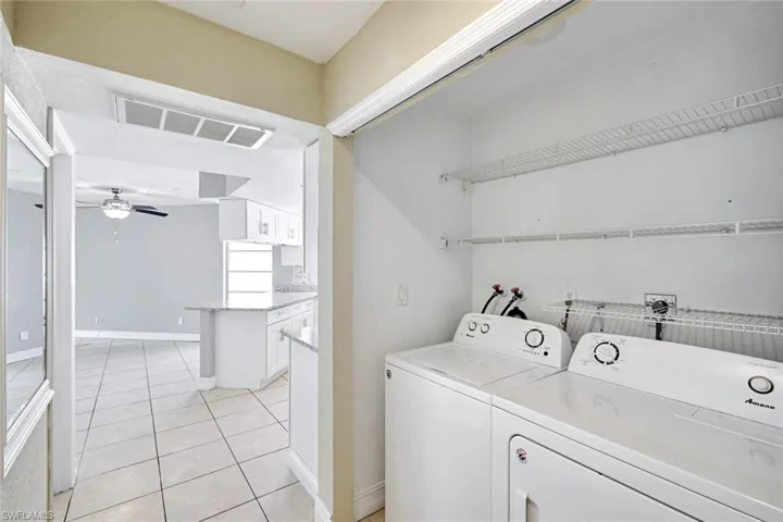 Laundry area featuring light tile patterned floors, a ceiling fan, and washing machine and dryer