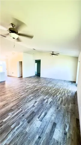Spacious interior featuring wood-finish flooring, vaulted ceilings, and ceiling fans
