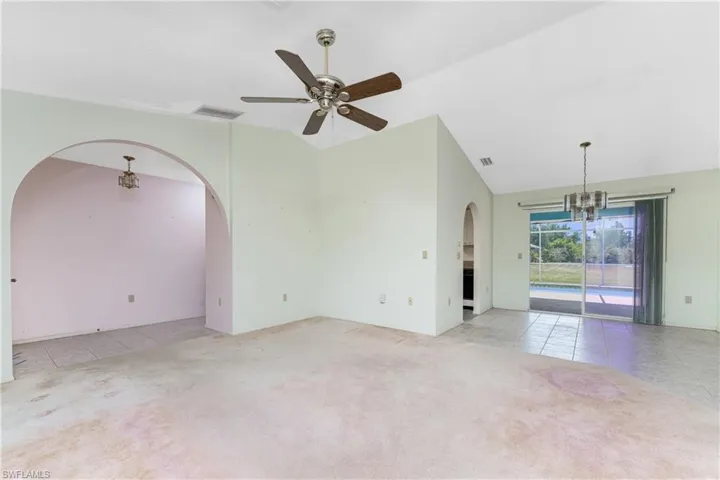 Kitchen featuring stainless steel appliances, ceiling fan with notable chandelier, light wood-type flooring, and lofted ceiling