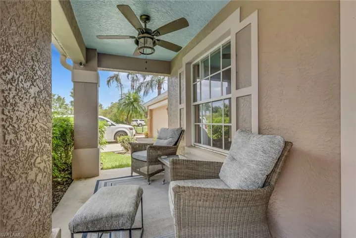 Covered front porch featuring a ceiling fan, light blue ceiling, textured stucco exterior, and a large window with white framing