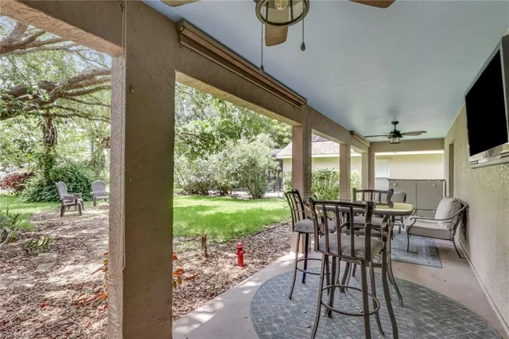 Covered patio featuring recessed lighting, multiple ceiling fans, and an outdoor kitchen area