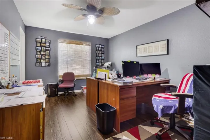 Dedicated office space featuring wood-finish flooring and a central window with woven shades