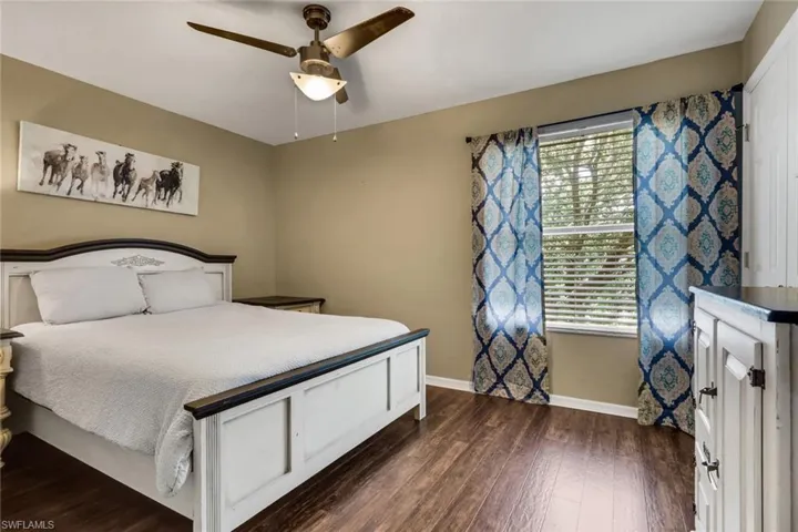 Interior room featuring wood-finish flooring, a ceiling fan with integrated lighting, and a window with blinds