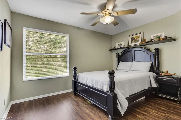 Spacious room featuring wood-finish flooring, a ceiling fan with integrated lighting, a large window with blinds, and neutral wall tones