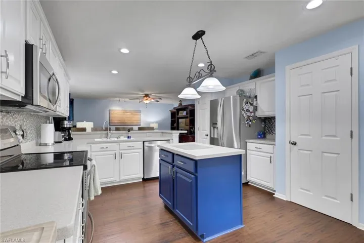 Kitchen featuring a blue island, white cabinetry, and wood-finish flooring