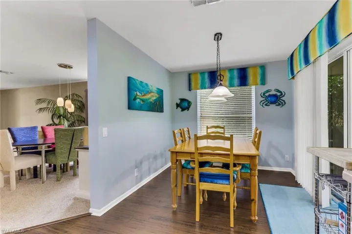 Dining area featuring wood-finish flooring, a window with horizontal blinds, and a glass-paned sliding door