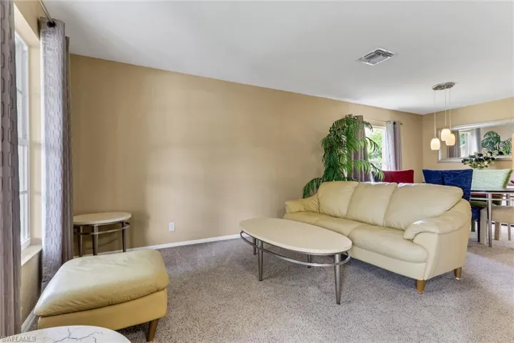 Carpeted living space with neutral wall tones and a window offering natural light