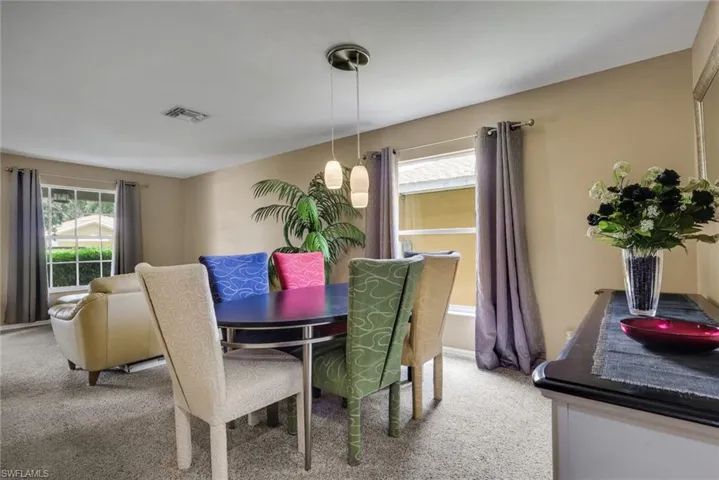 Dining area featuring a contemporary pendant light fixture, neutral wall tones, and carpeted flooring