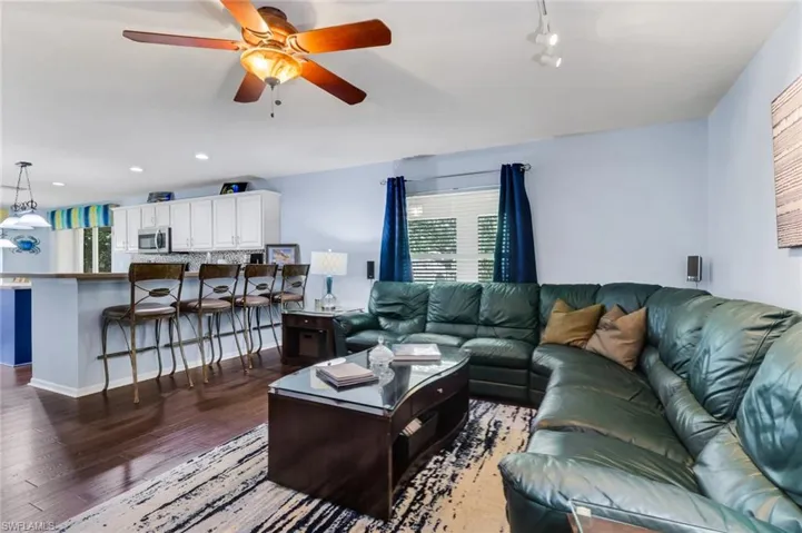 Open-concept living area featuring wood-finish flooring, a ceiling fan with integrated lighting, and recessed ceiling lights