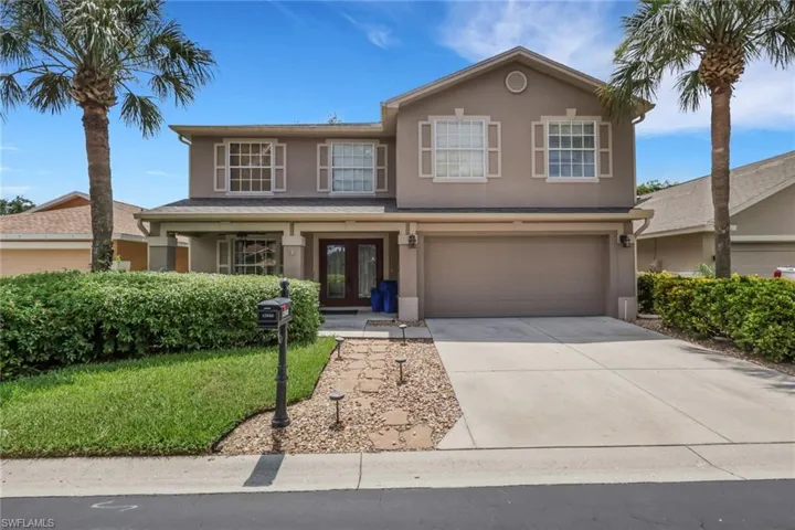 Two-story stucco residence featuring a covered entry, double-door main entrance, and an attached two-car garage