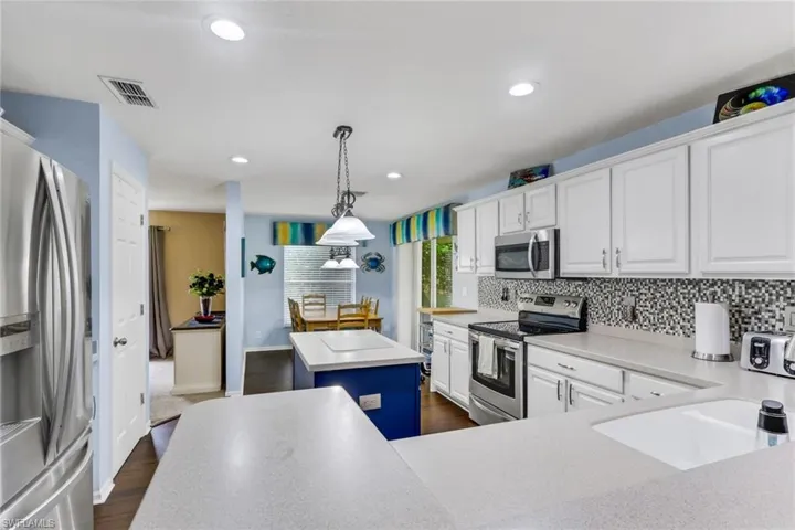 Kitchen featuring white cabinetry, light-toned countertops, a mosaic tile backsplash, and stainless steel appliances