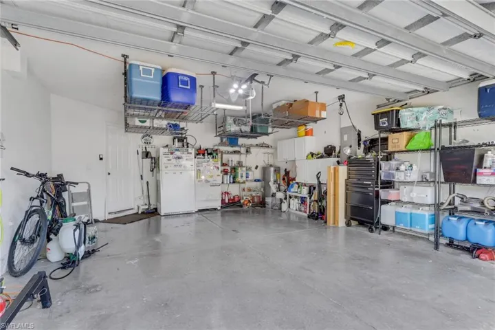 Spacious garage featuring a finished concrete floor, overhead shelving, and a paneled white door