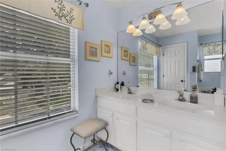 Double vanity featuring white cabinetry, integrated sinks, chrome fixtures, and a full-width mirror with track lighting