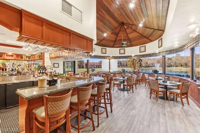 Bar featuring wood ceiling, light stone counters, ceiling fan, brown cabinetry, and a water view