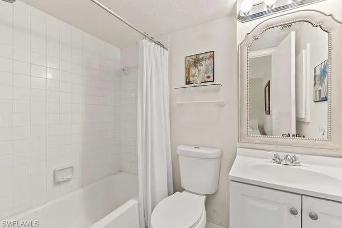 Bathroom with shower / bath combination with curtain and vanity