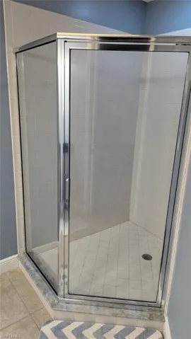 Full bath with a shower stall and light tile patterned floors