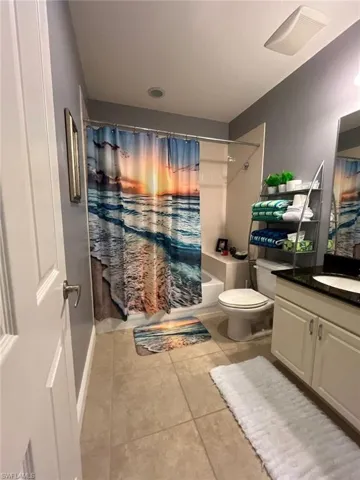Bathroom with vanity, shower / tub combo, and light tile patterned flooring