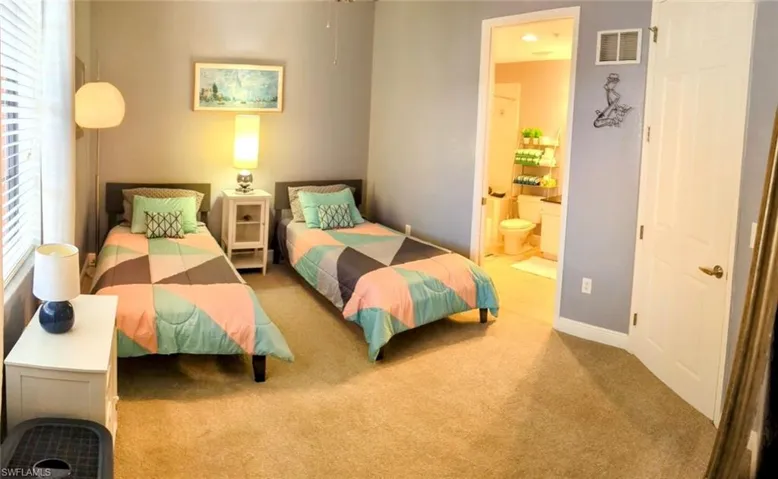 Carpeted bedroom with ensuite bath and baseboards
