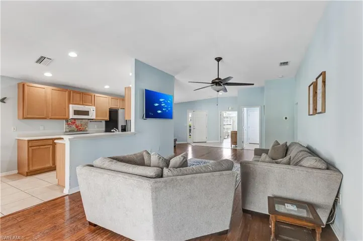 Living room featuring light wood-type flooring, a ceiling fan, recessed lighting, baseboards, and vaulted ceiling