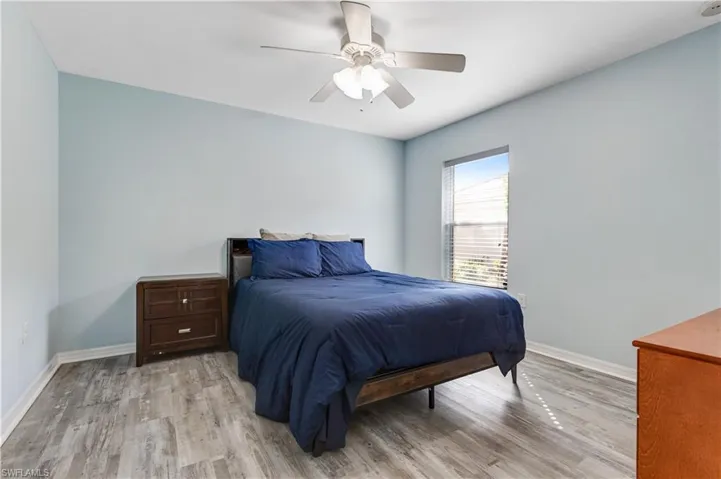 Bedroom with light wood finished floors, baseboards, and ceiling fan