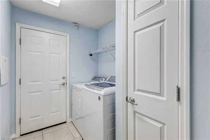 Laundry room with separate washer and dryer and light tile patterned flooring