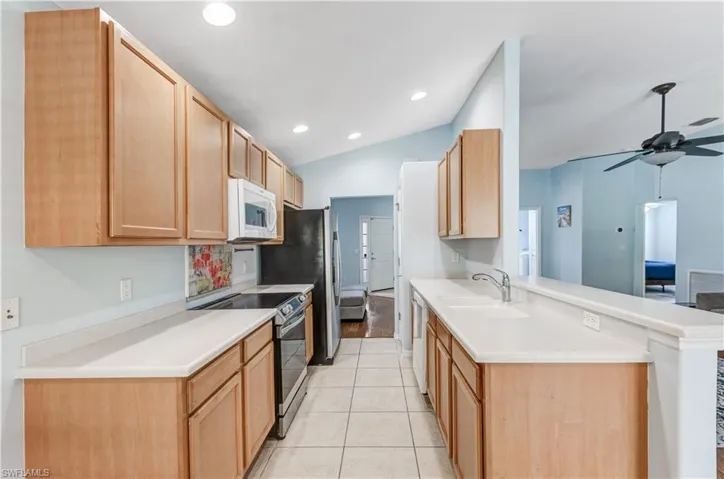 Kitchen featuring white microwave, stainless steel electric range oven, a sink, a peninsula, and ceiling fan