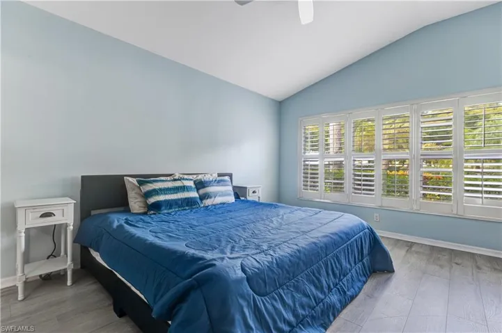 Bedroom with wood finished floors, vaulted ceiling, baseboards, and a ceiling fan