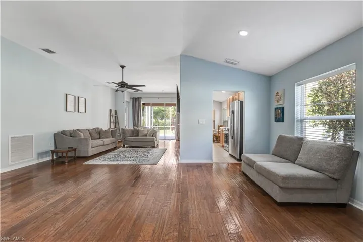 Living area featuring hardwood / wood-style flooring, baseboards, ceiling fan, and vaulted ceiling
