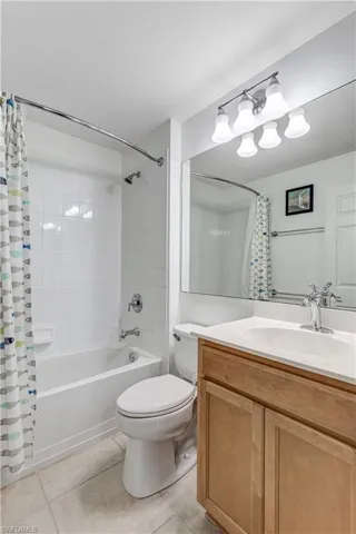 Bathroom featuring tile patterned floors, shower / tub combo with curtain, toilet, and vanity