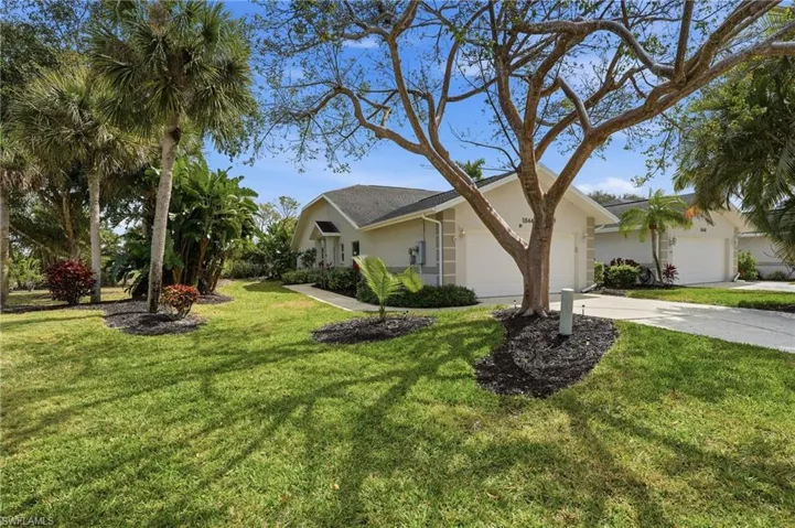 View of side of property with stucco siding, concrete driveway, a garage, and a yard