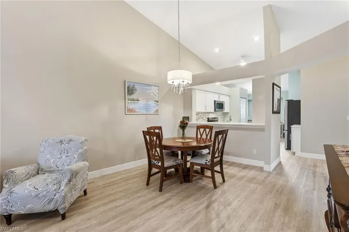 Dining area with light wood-style floors, vaulted ceiling, and a chandelier