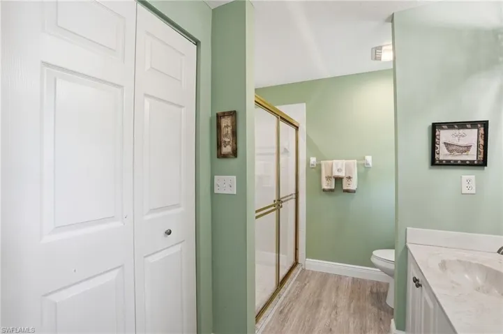 Bathroom with a stall shower, vanity, light wood-type flooring, and a closet