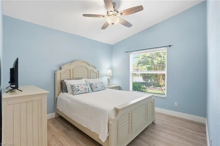 Bedroom featuring light wood-style flooring, vaulted ceiling, and a ceiling fan