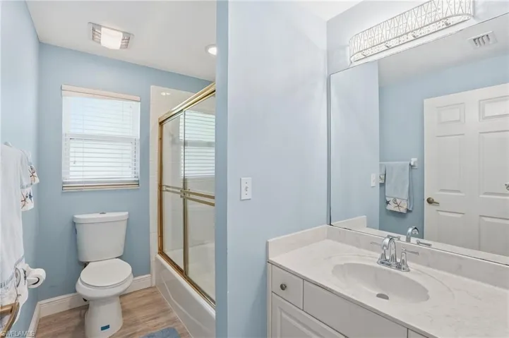 Full bathroom featuring enclosed tub / shower combo, vanity, and light wood finished floors