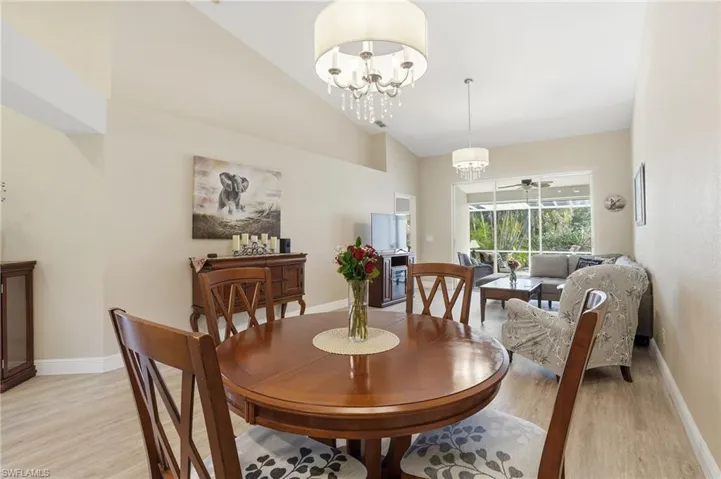 Dining room featuring light wood-type flooring, a ceiling fan, hanging lights, and vaulted ceiling