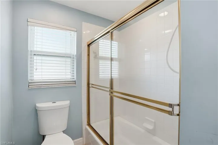 Full bath with enclosed tub / shower combo and toilet