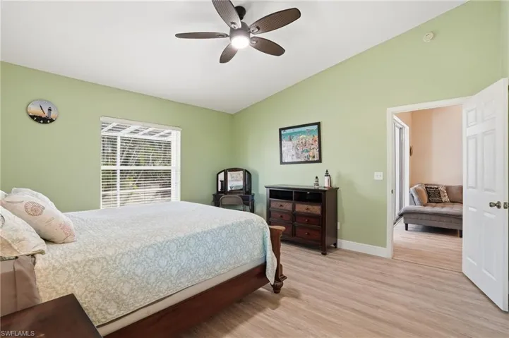 Bedroom with lofted ceiling, light wood finished floors, and a ceiling fan