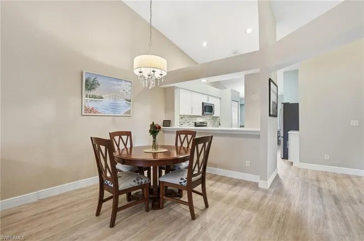 Dining area with light wood-type flooring, lofted ceiling, and a chandelier