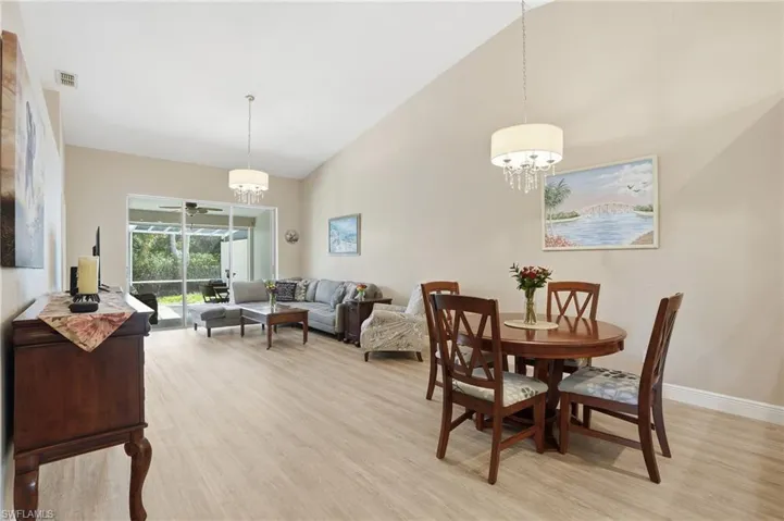 Dining area featuring light wood finished floors, a chandelier, lofted ceiling, and a ceiling fan