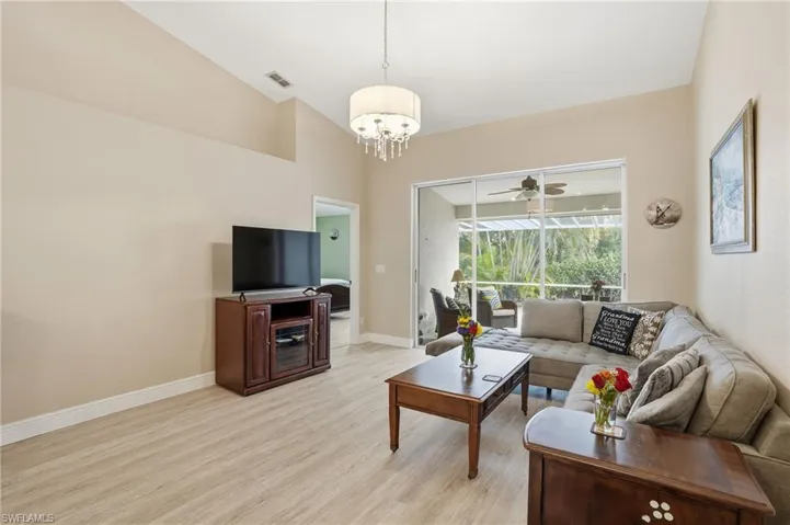 Living room with light wood finished floors, a ceiling fan, lofted ceiling, and hanging lights