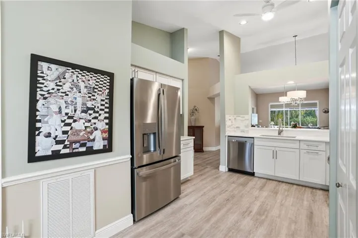 Kitchen with stainless steel appliances, suspended lighting, white cabinetry, a ceiling fan, and a high ceiling