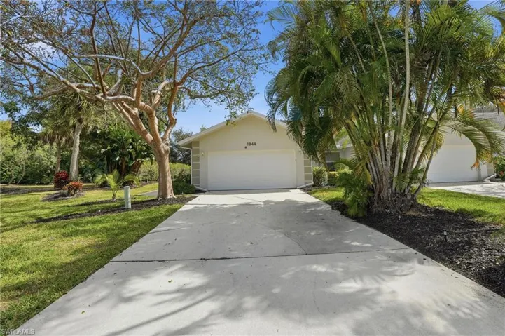 View of front of home featuring driveway, a front lawn, stucco siding, and a garage