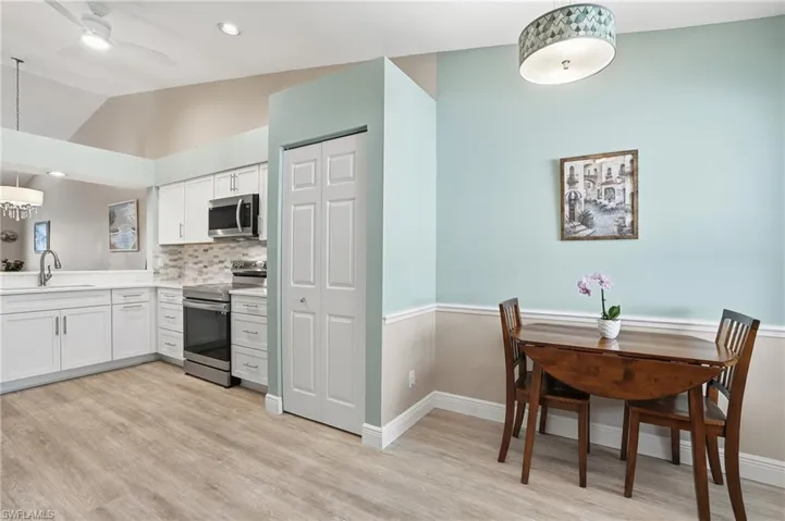 Kitchen with pendant lighting, stainless steel appliances, white cabinets, ceiling fan, and backsplash