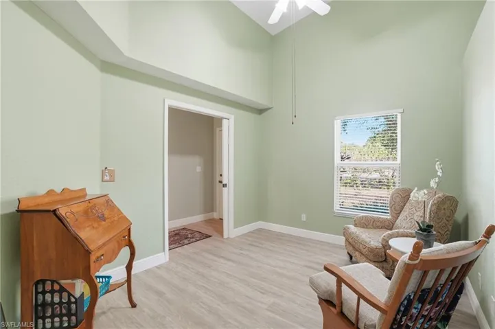 Sitting room with light wood finished floors, vaulted ceiling, and ceiling fan