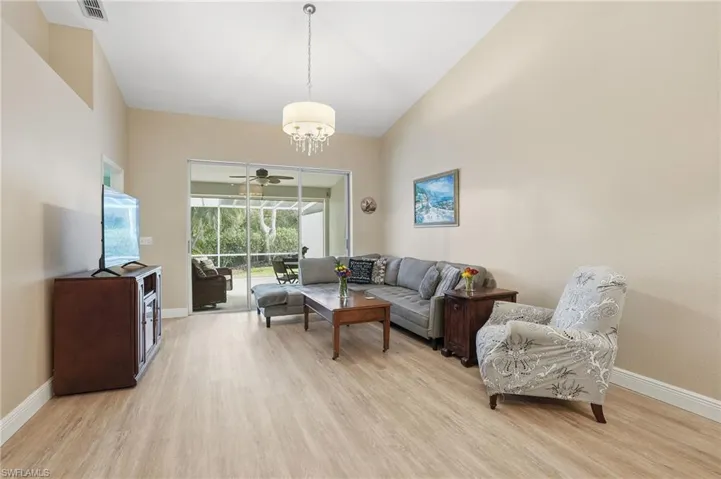 Living area with light wood finished floors, a ceiling fan, lofted ceiling, and suspended lighting