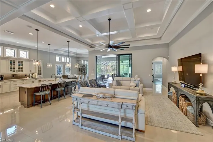 Tiled Great room featuring coffered ceiling, ceiling fan, ornamental molding, beam ceiling,