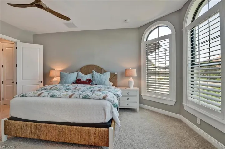 Carpeted bedroom featuring ceiling fan and shutters