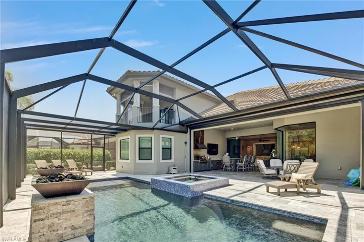 View of pool featuring a patio, a lanai, an in ground hot tub, sun shelf