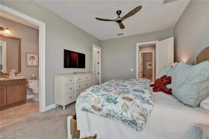 Carpeted bedroom featuring connected bathroom and ceiling fan